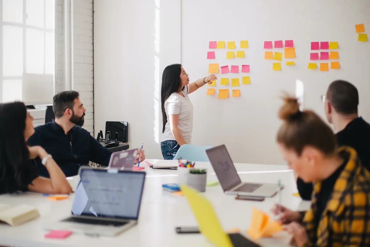 People in an office in a meeting room using sticky post its.