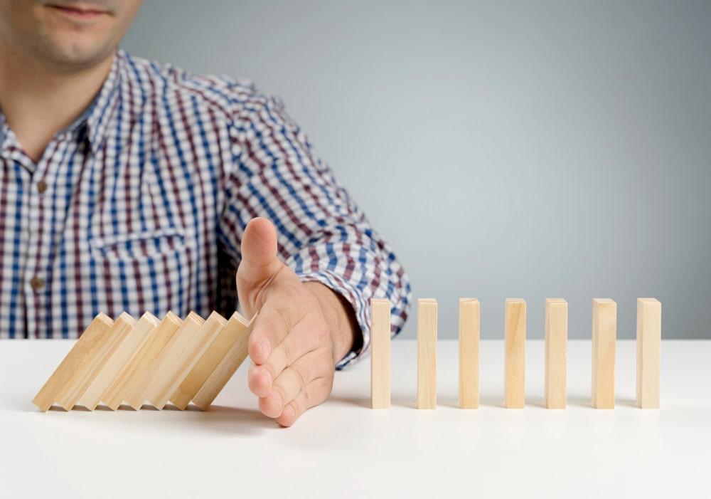 Prevent domino effect - metaphorical illustration for preventing the cascading effects of competing priorities.